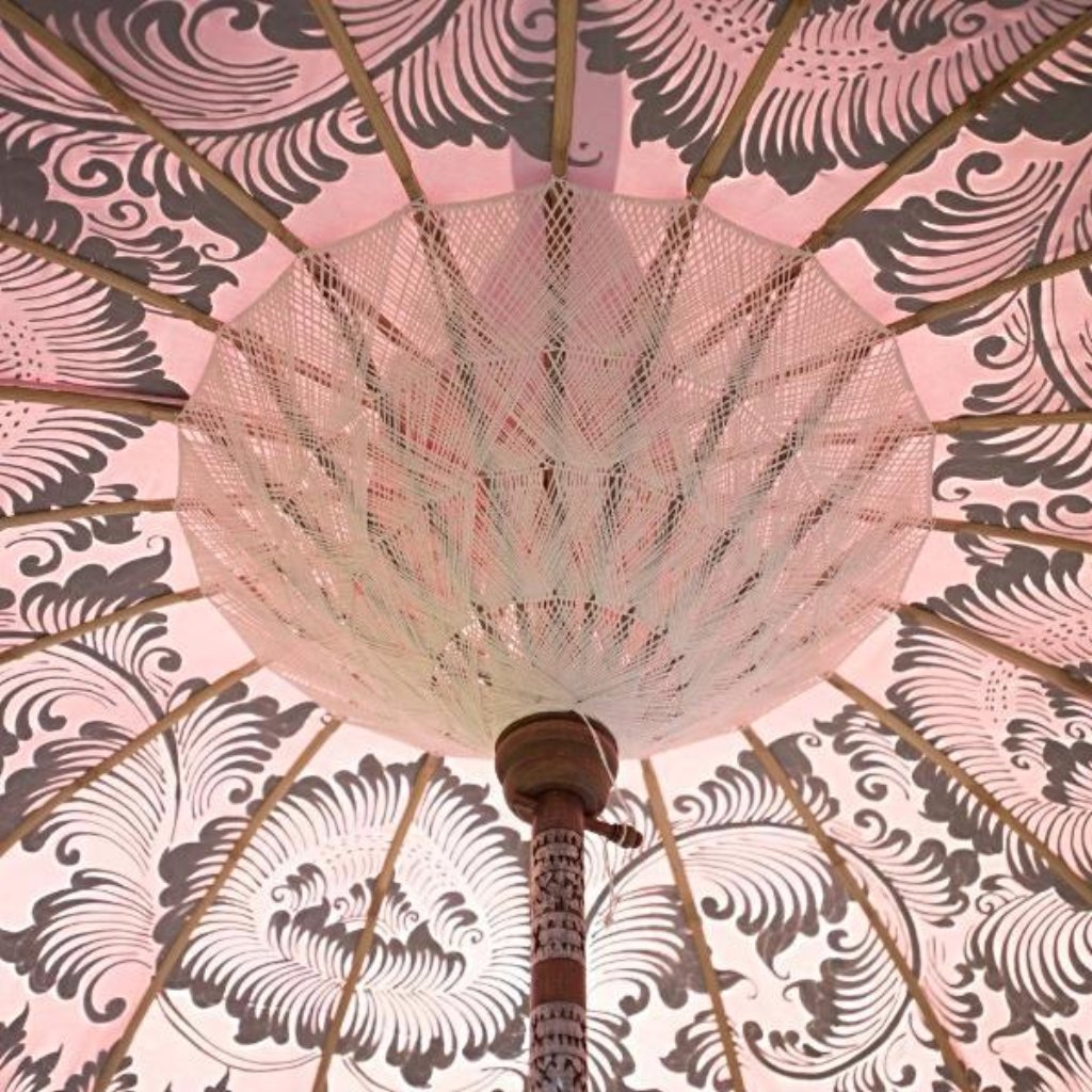 Stevie Round Bamboo Parasol- Pale pink twill garden parasol with floral design hand painted in silver ink. The pole is made from hand-carved durian wood pole with silver paint and finial, the pole join and pegs are made from solid brass with white threading, bamboo spokes.