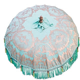 Tracy Round Bamboo Parasol - Beautiful light green twill garden parasol with lotus design hand-painted in gold ink. The pole is made from hand-carved durian wood pole with gold paint and finial, the pole join and pegs are made from solid brass. The parasol has muted turquoise threading and bamboo spokes. Hand-made green and light blue fringing, with beaded green tassels.