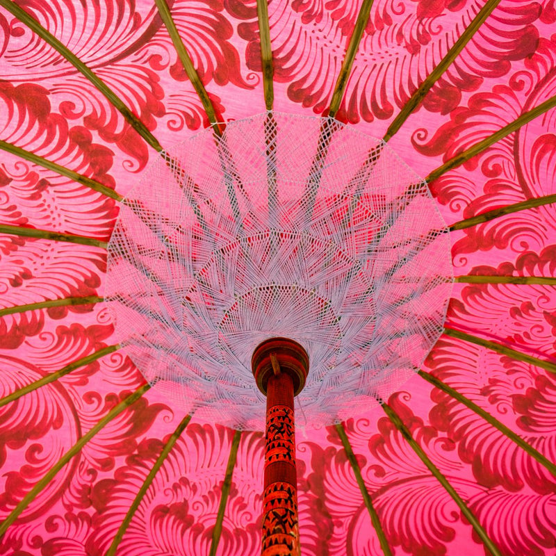 Heidi Round Bamboo Parasol is a blossom pink twill umbrella with lotus design hand-painted in gold ink. White threading inside and bamboo spokes. The pole is made from hand-carved durian wood pole with gold paint and finial, the pole join and pegs are made from solid brass. The fringing is in white with gorgeous white tassels and gold beading.