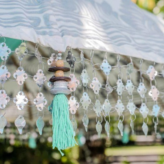 Cher white cream silver and mint green blue  garden parasol or umbrella hand painted with silver. Bamboo spokes, hand carved durian wood pole, Indian metal silver fringing and light blue cotton tassels. Pretty garden umbrella for picnics, gardens, festivals, weddings, terraces and pool side. Beautiful boho, bali parasol.