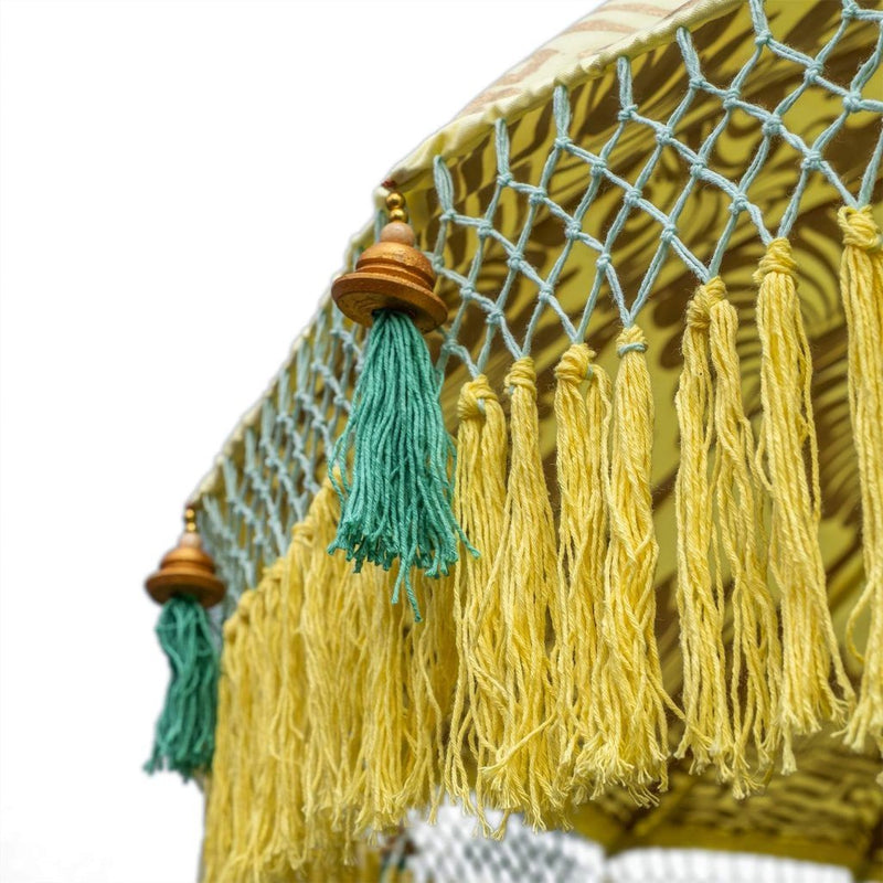 Goldie Round Bamboo Parasol is a lovely yellow twill with lotus design hand-painted in gold ink. Sea green threading and bamboo spokes. The pole is made from hand-carved durian wood pole with gold paint and finial, the pole join and pegs are made from solid brass. The fringing is in shades of vibrant primrose yellow with muted green tassels to match the interior threading.