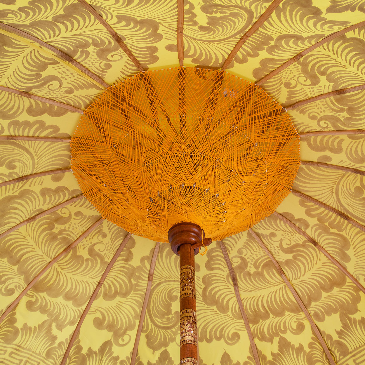 Dayla Round Bamboo Parasol has orange threading inside and bamboo spokes. The pole is made from hand-carved durian wood pole with gold paint and finial, the pole join and pegs are made from solid brass. The fringing is in pink with elegant orange tassels and gold beading.