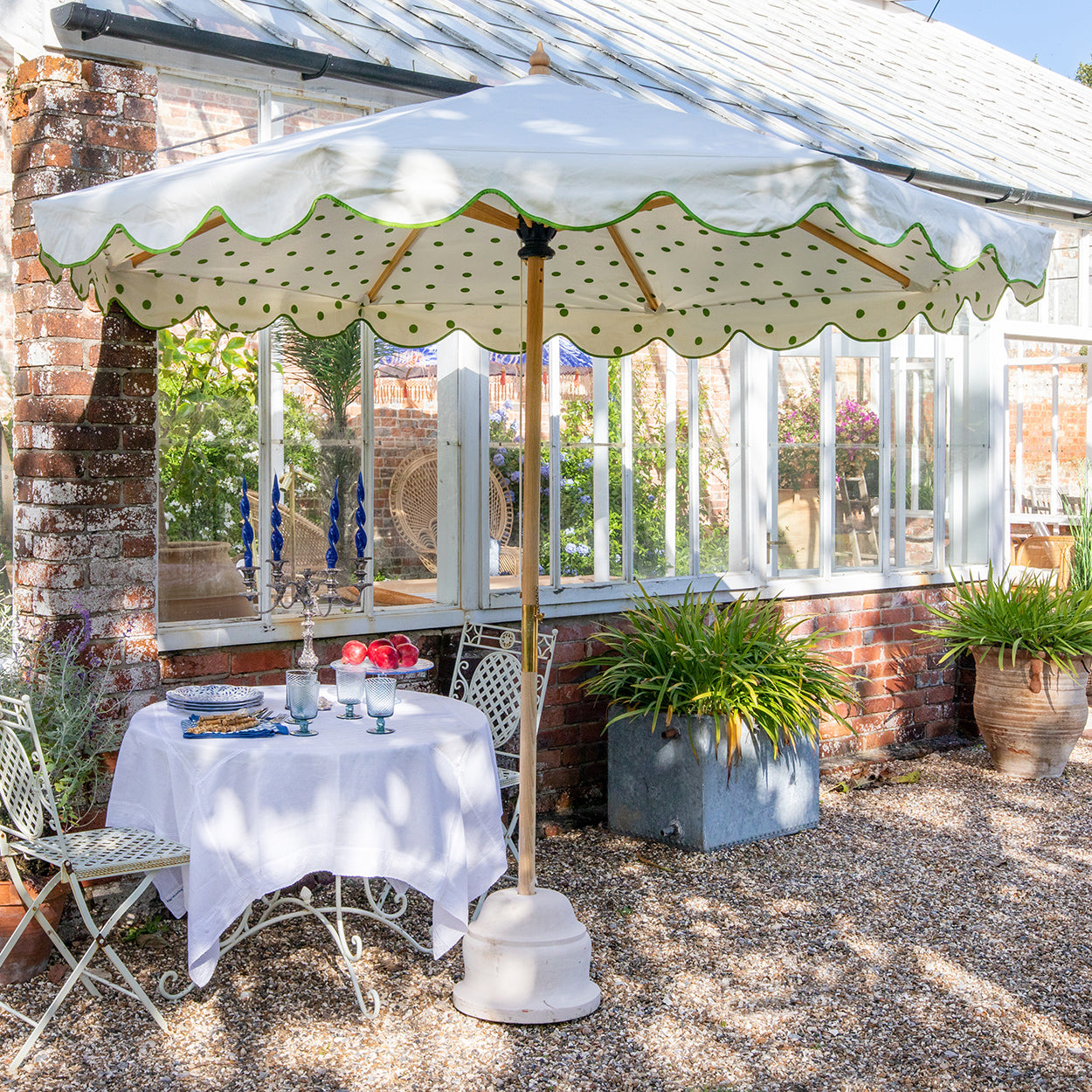 Lifestyle image of Grace 2 Octagonal Parasol handcrafted frame made in the UK. Natural cotton canvas with white canopy, printed green polka dot pattern inside and scalloped valance.