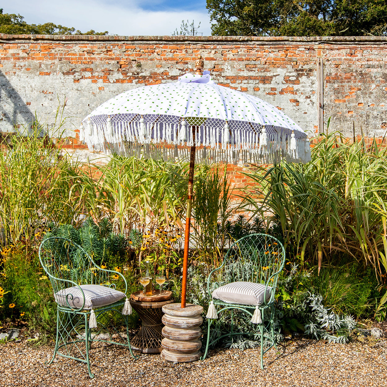 Grace Round Bamboo Parasol is elegant white canopy with green polka dots. Yellow threading inside and bamboo spokes. The pole is made from hand-carved durian wood pole with gold paint and finial, the pole join and pegs are made from solid brass. The fringing is in white with sophisticated white tassels and beading.