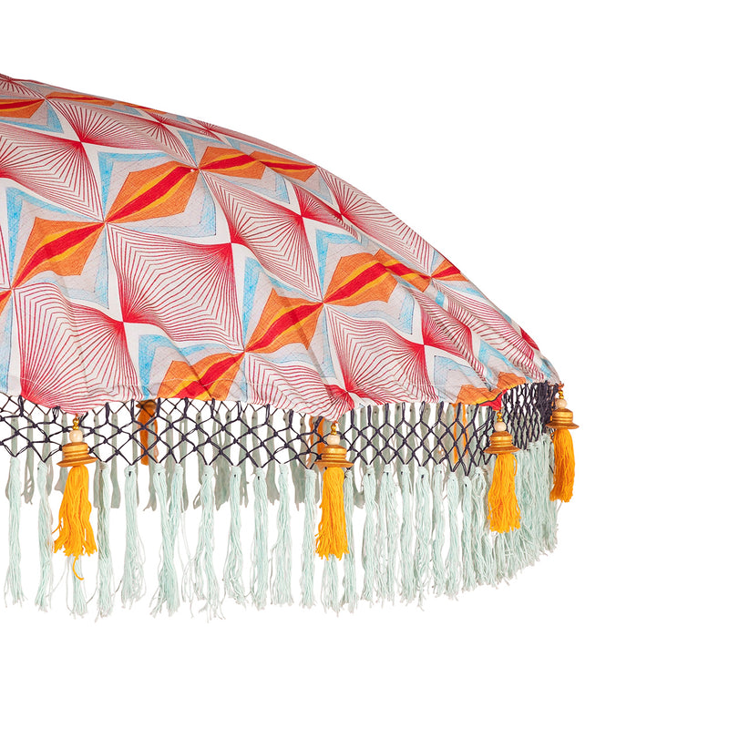 Roo Round Bamboo Parasol- geometric printed canopy with orange threading, light blue fringing and orange tassels. The pole is made from hand-carved durian wood pole with gold paint and finial, the pole join and pegs are made from solid brass.