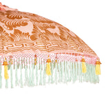 Rosanna Round Bamboo Parasol's canopy is a gorgeous pastel pink with lotus design hand-painted in gold ink.  Inside the threading is light yellow, and the fringe is a combination of mint green and light yellow tassels. The pole is made from hand-carved durian wood pole with gold paint and finial, the pole join and pegs are made from solid brass.