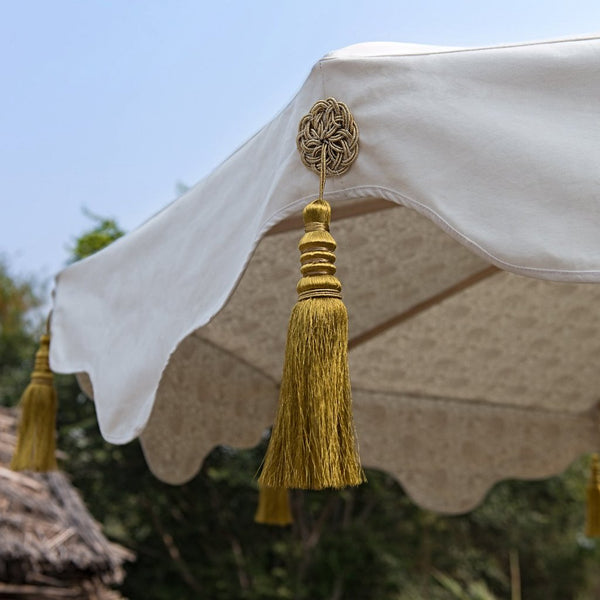 Big Liberace, stunning 3m wooden frame cream and gold garden parasol. Natural cotton canvas with gold block print inside and luxurious gold tassels. The edges are an arabian-influenced shape with handmade adornments. The canopy is removable. The ultimate garden decoration. Perfect show stopping garden umbrella for an elegant dining area or pool, or beside a sun lounger, for an event or wedding.