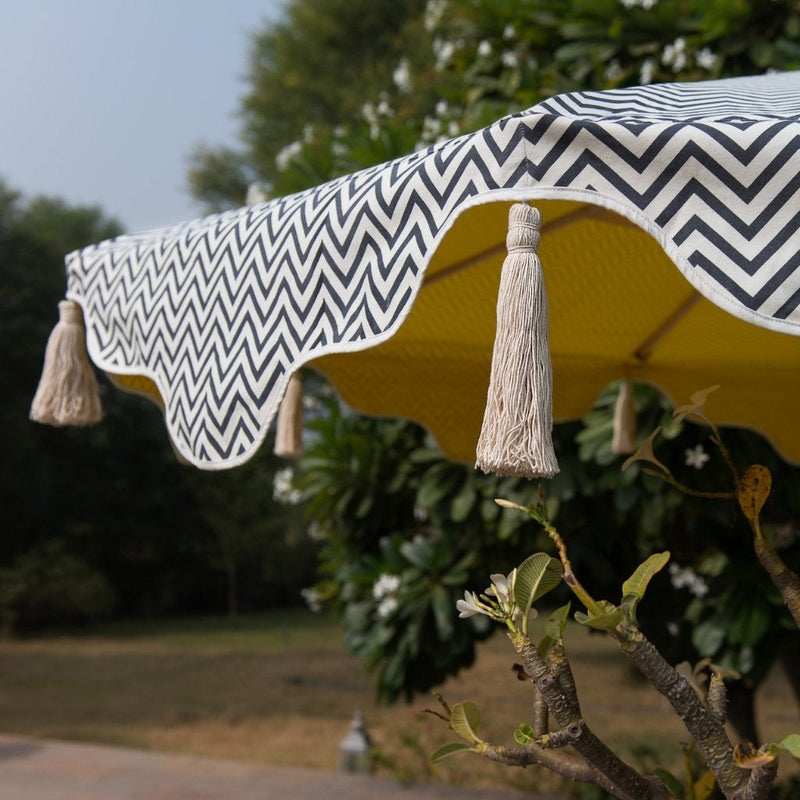 3m Zigzag and yellow garden parasol. Block printed natural coloured waterproof cotton canvas with charcoal zig zags and primrose yellow and a wooden garden umbrella frame of 3m. The edges are an arabian-influenced shape with handmade natural cotton tassles.  Perfect  show stopping garden umbrella for an elegant garden or pool. The most fabulous garden decoration.
