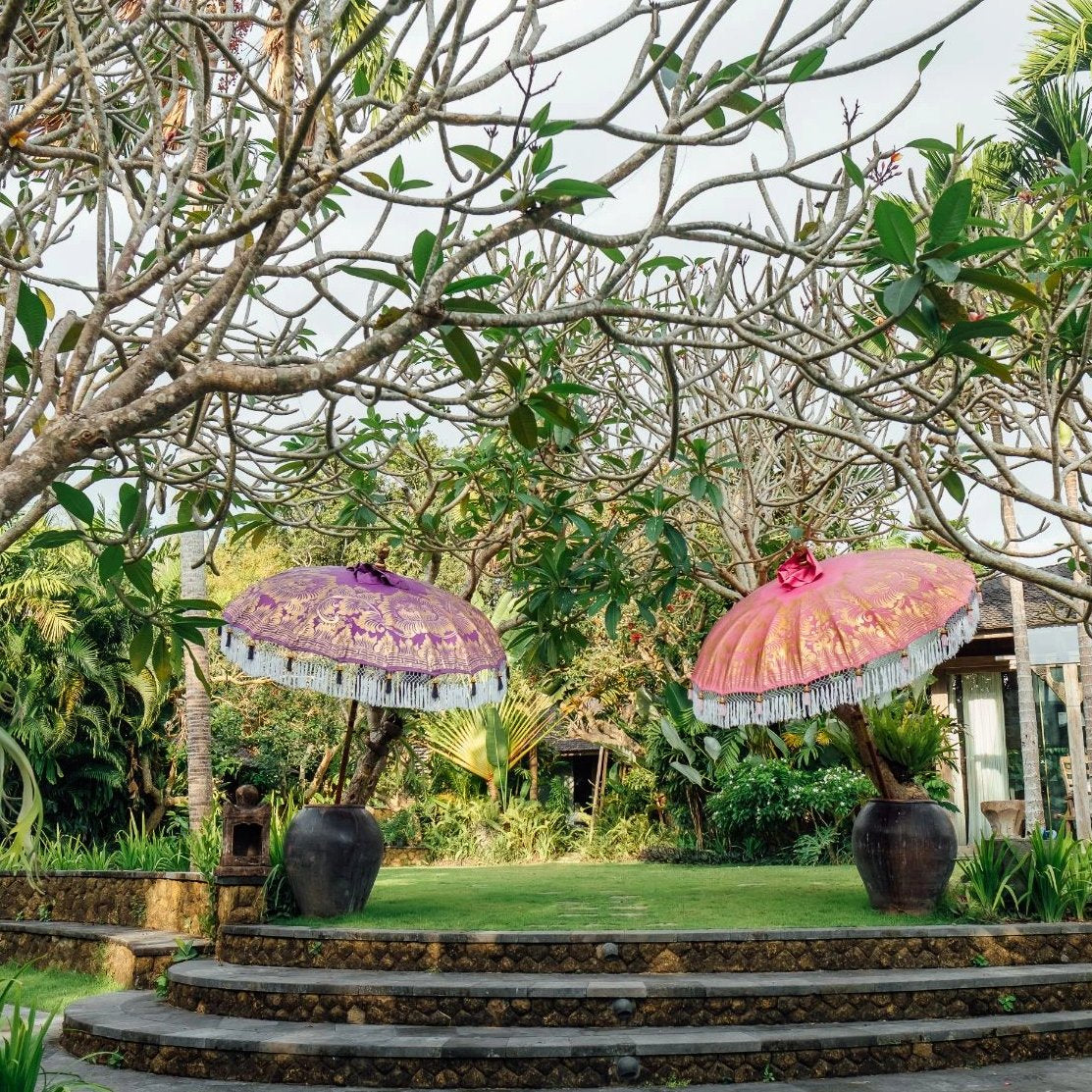 Heidi Round Bamboo Parasol is a blossom pink twill umbrella with lotus design hand-painted in gold ink. White threading inside and bamboo spokes. The pole is made from hand-carved durian wood pole with gold paint and finial, the pole join and pegs are made from solid brass. The fringing is in white with gorgeous white tassels and gold beading.