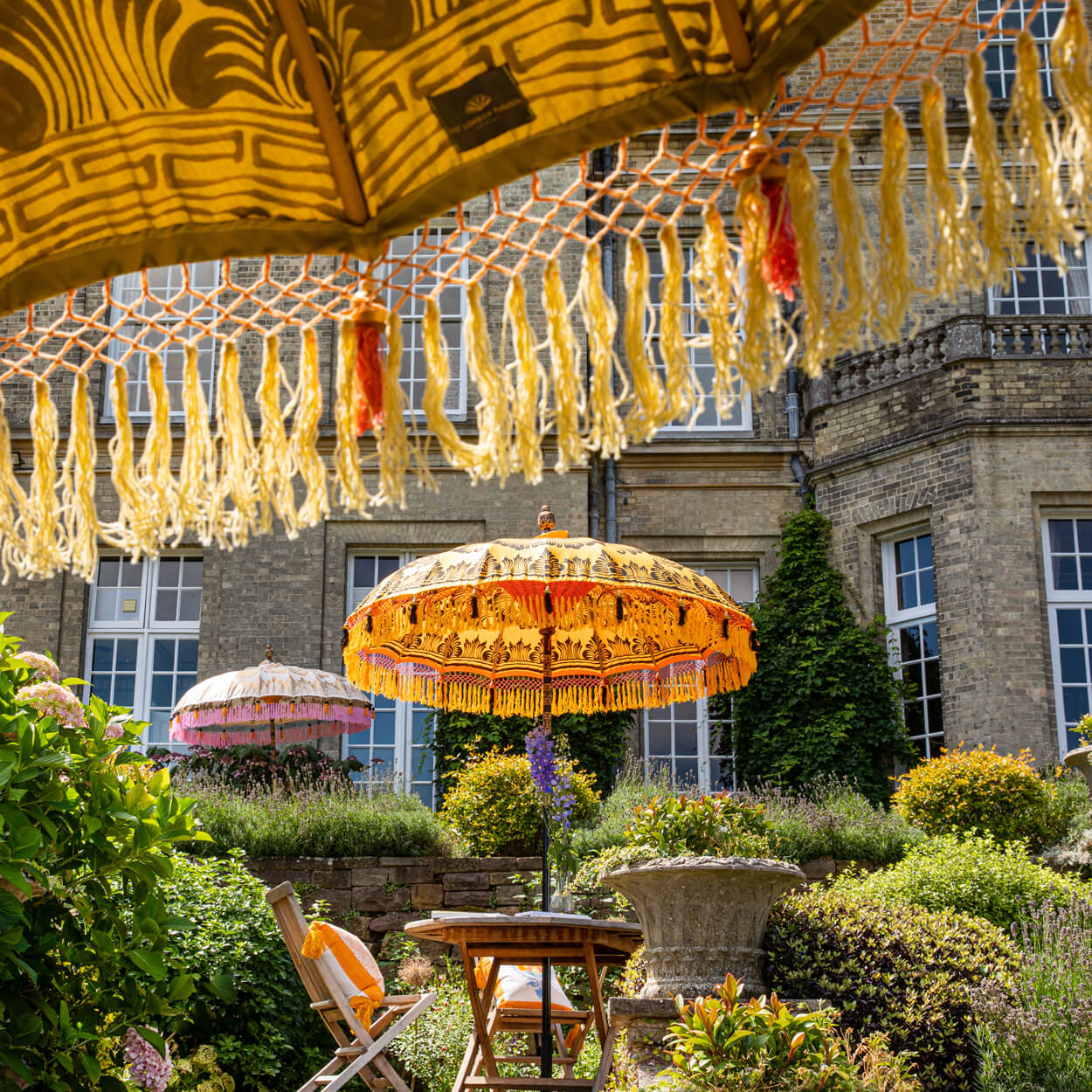 Augusta Round Bamboo Parasol has dark orange threading inside and bamboo spokes. The pole is made from hand-carved durian wood pole with gold paint and finial, the pole join and pegs are made from solid brass. The fringing is in orange with yellow tassels and beading. These are handmade items and there may be some variation in colour.