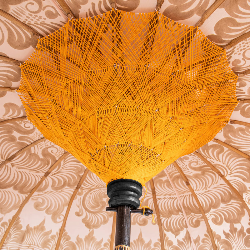 Helena Round Bamboo Parasol - soft beige twill with lotus design hand-painted in gold ink. Inside the threading is vibrant tangerine orange, and the fringe is a combination of peony pink, black and orange tassels. 