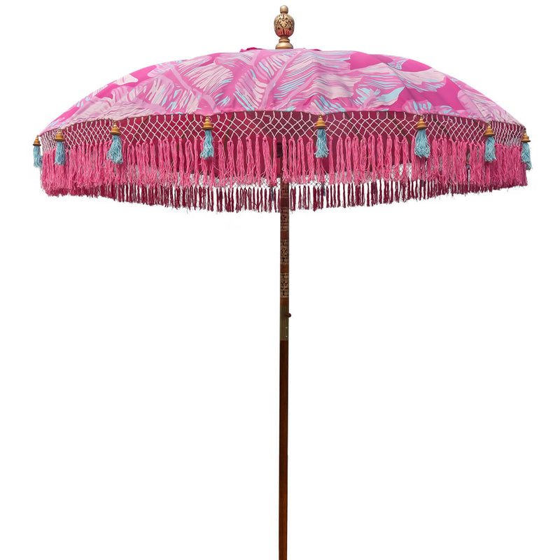 Pink Nina Round Bamboo Parasol- Show-stopping bright pink waterproof canvas umbrella digitally printed with a palm print and banana leaf design in shades pink and blue accents. This is a unique piece and utterly tropical flamboyant garden parasol, blending together the best of modern textile technology and traditional craftsmanship.